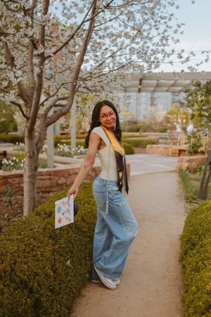 Casual outdoor photoshoot showing playful poses along a garden path with overalls and yellow top.