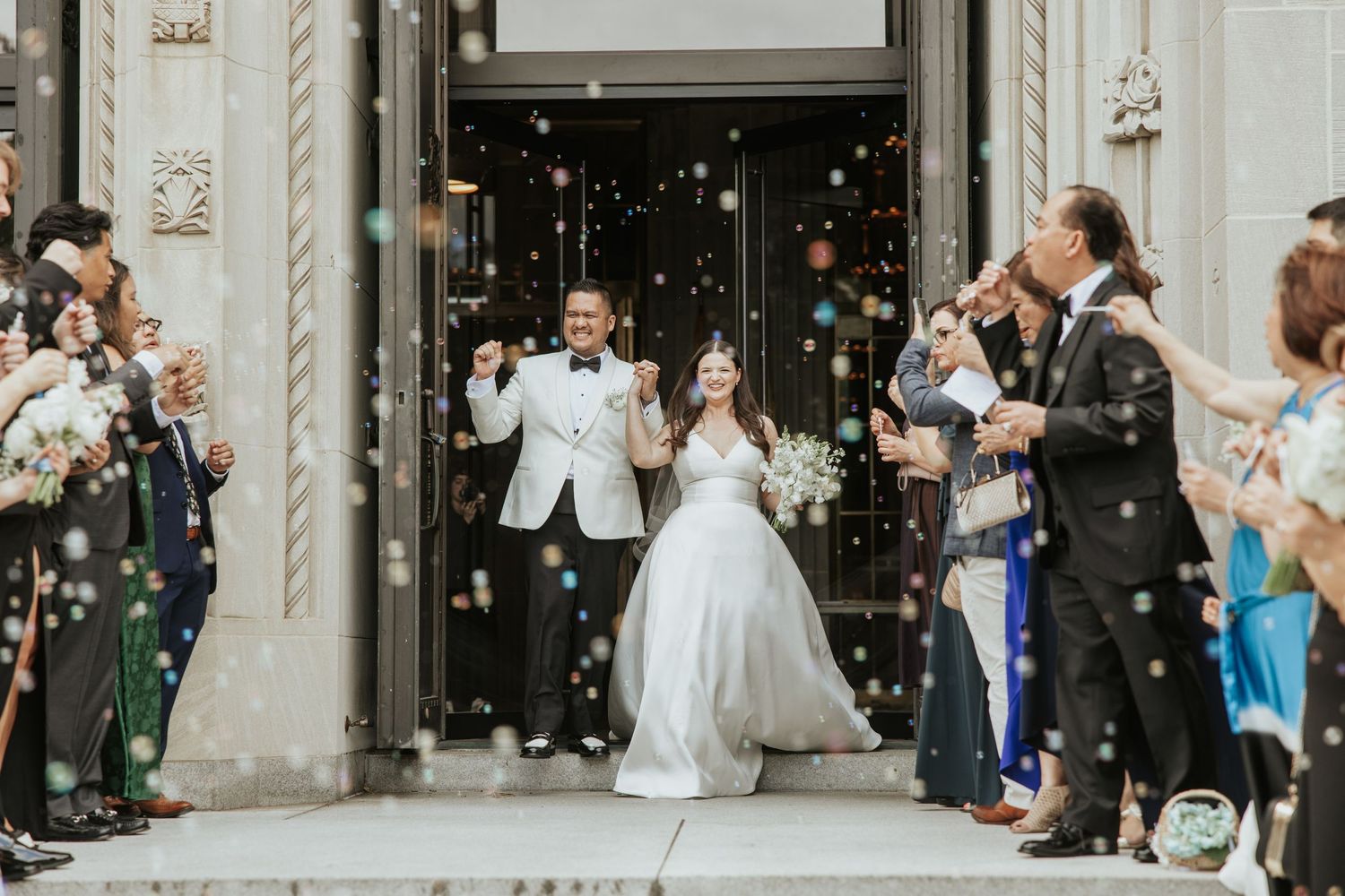 Newlyweds exit church while guests throw confetti in joyous celebration.