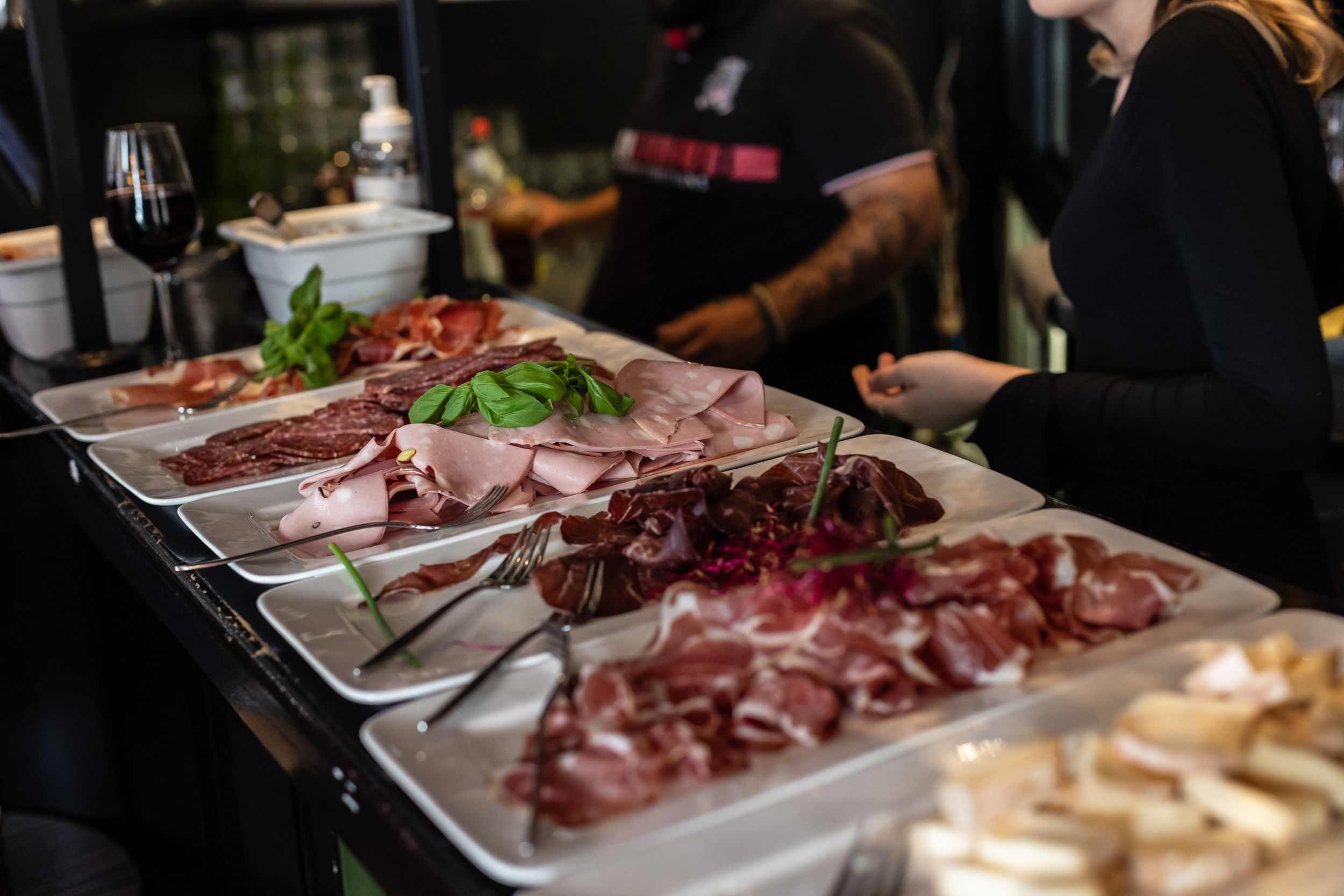Charcuterie board with various sliced meats and garnishes arranged on serving platters.