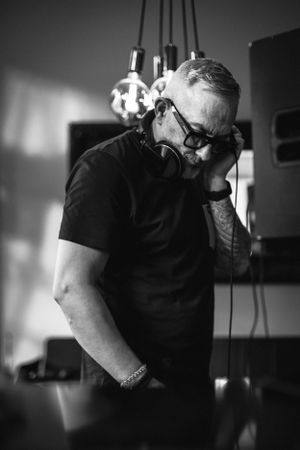 DJ in black shirt and sunglasses mixing music at a nightclub.