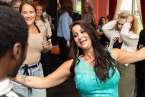 Enthusiastic dancers enjoying themselves at a crowded social gathering.