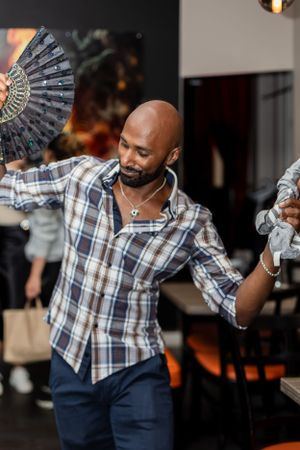Dancer holding decorative fan while performing expressive movements at a party.
