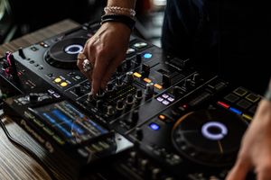 Close-up of hands operating professional DJ equipment with illuminated controls.
