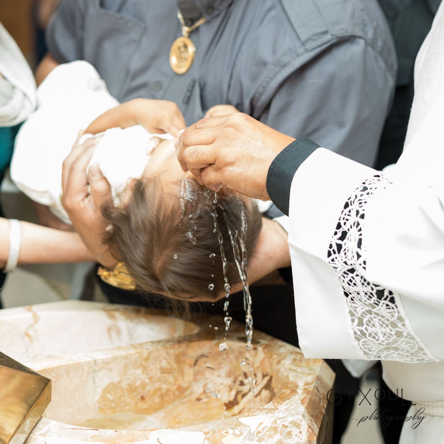 Holy baptism ceremony showing water being poured over an infant's head.