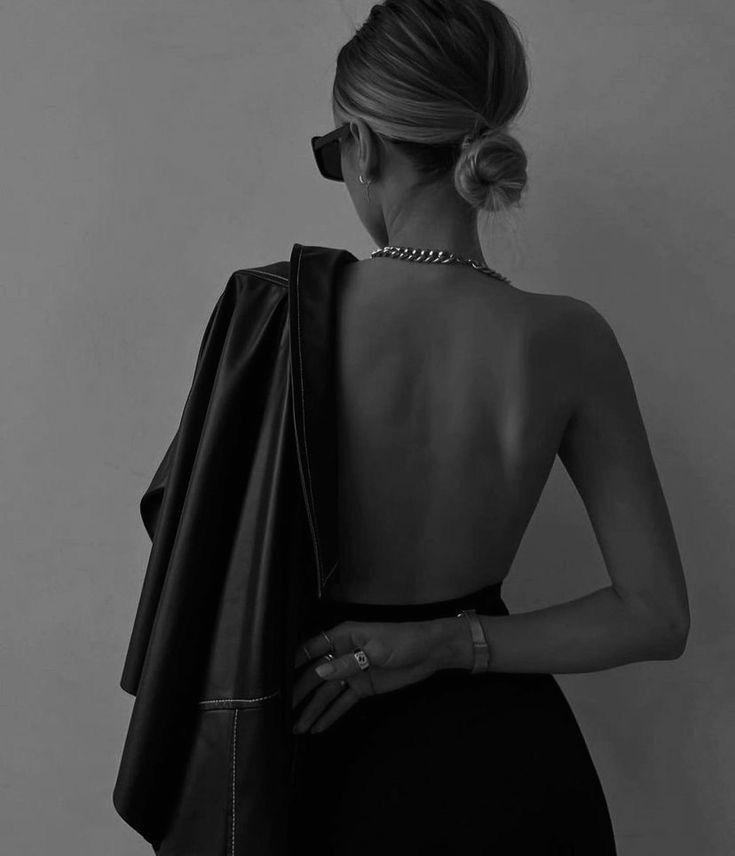 Elegant backless black dress shown from behind in dramatic monochrome styling.
