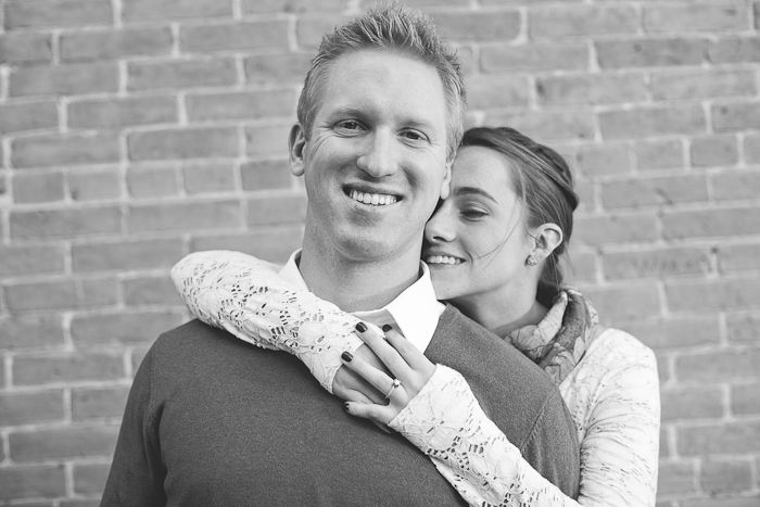 Black and white portrait of a couple against a brick wall background.
