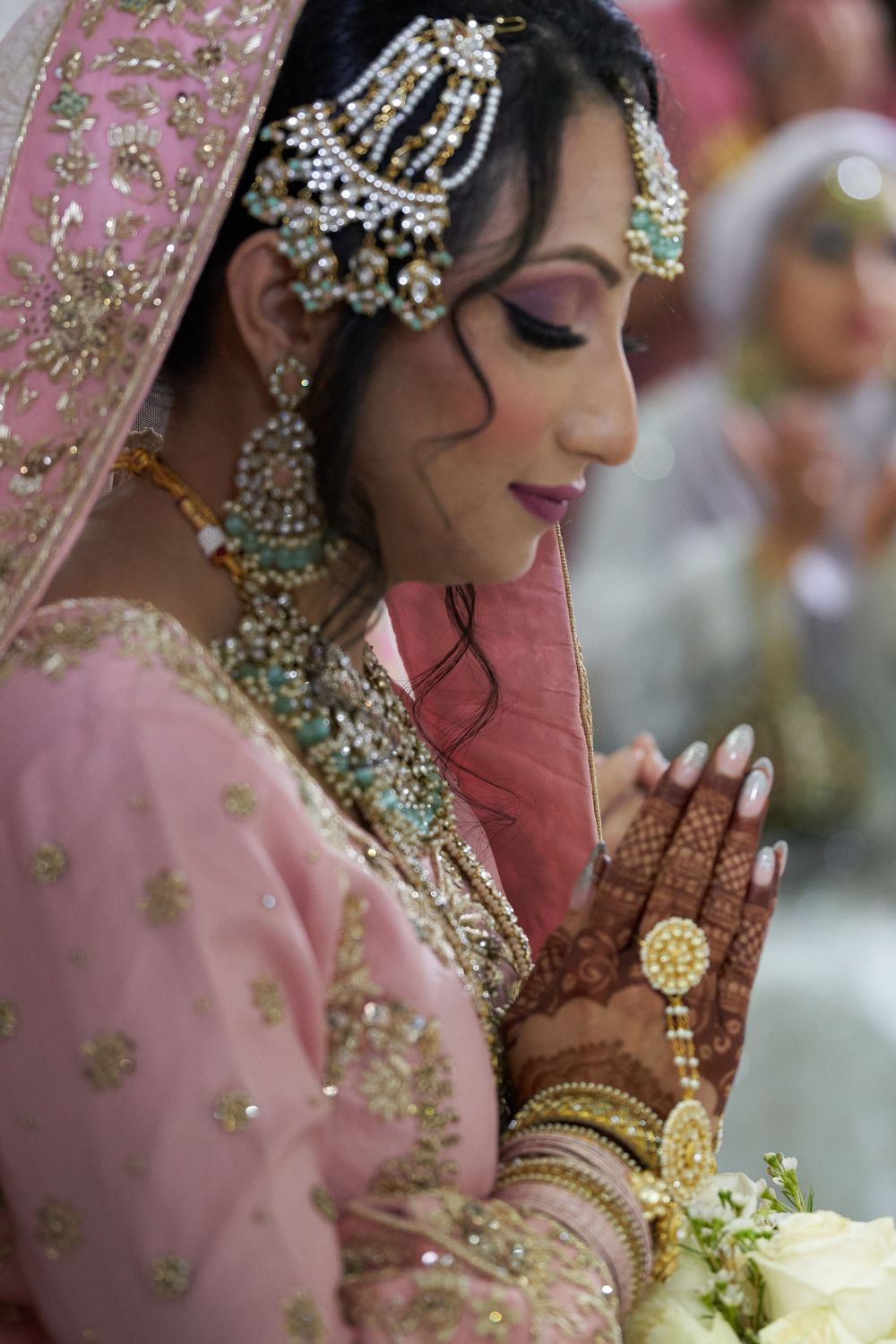 Traditional bridal jewelry and pink attire with delicate embroidery details.