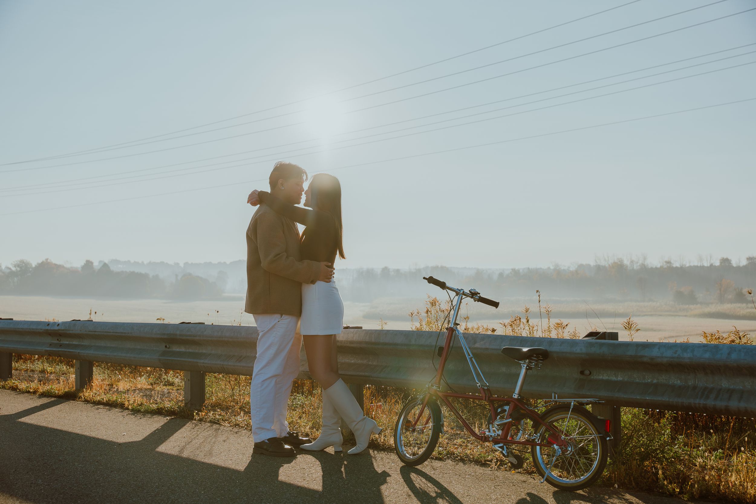 Silhouetted couple sharing a tender moment by their bicycle during golden hour.