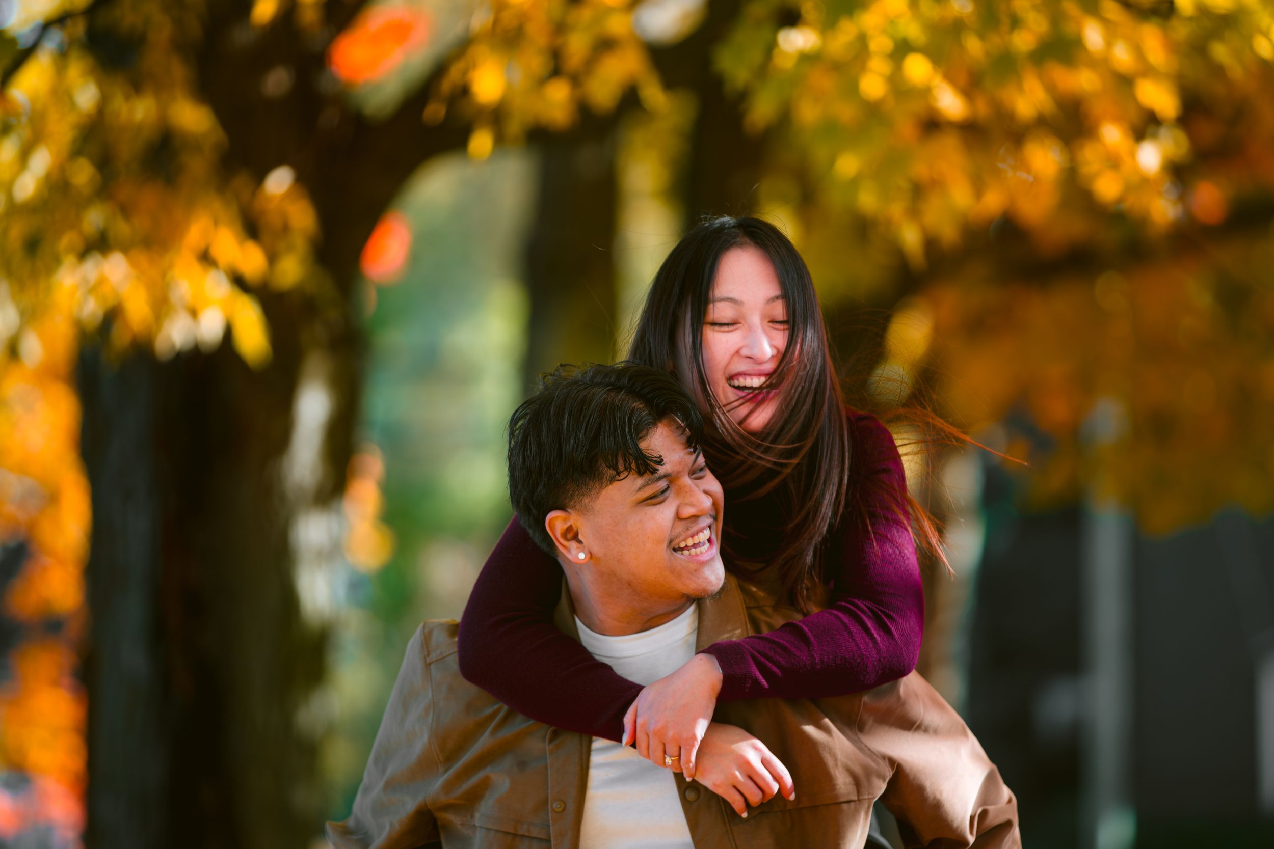 A playful autumn moment captured under golden maple trees on a sunny day.