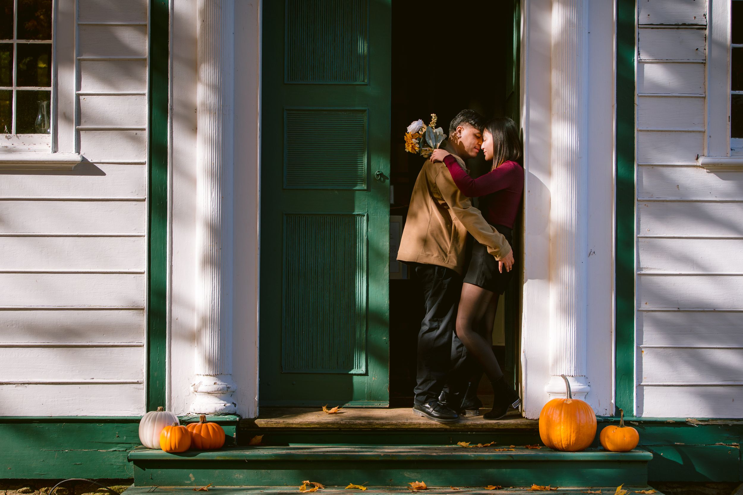 A romantic autumn scene on a porch with pumpkins and a green door.