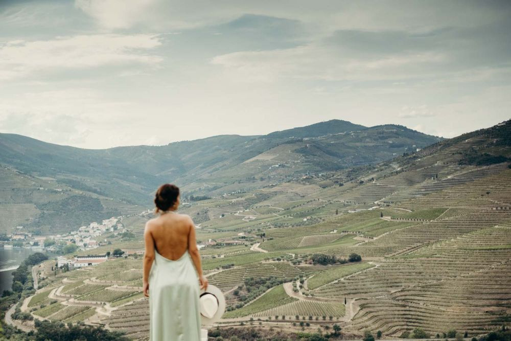 Cátia overlooks scenic terraced Douro Valley vineyards in Portugal in their couple shoot.
