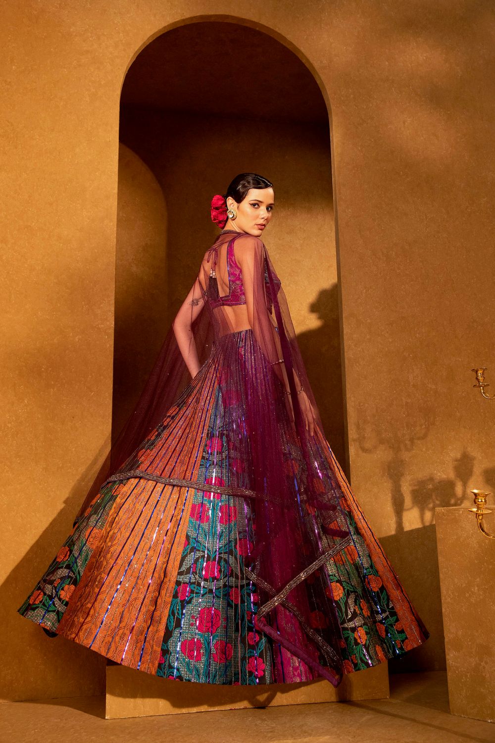 Model wearing vibrant multicolor embroidered lehenga choli with magenta dupatta and floral details in traditional Indian bridal wear.