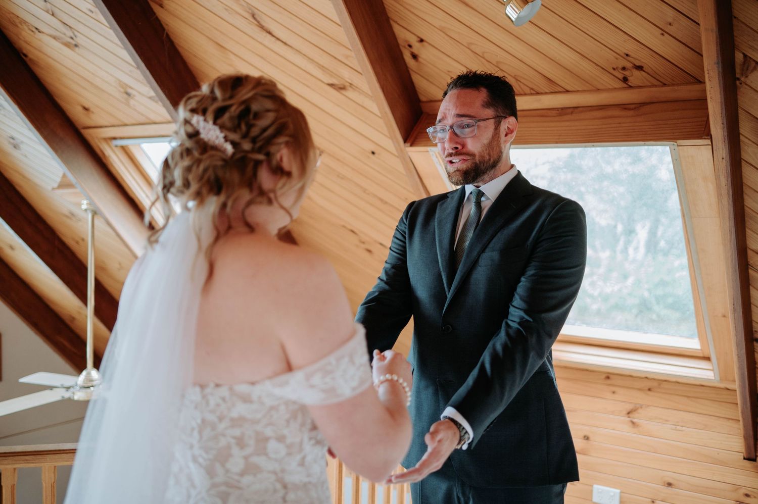 A tender first look moment between a couple in an A-frame cabin with wood paneled walls and large windows.