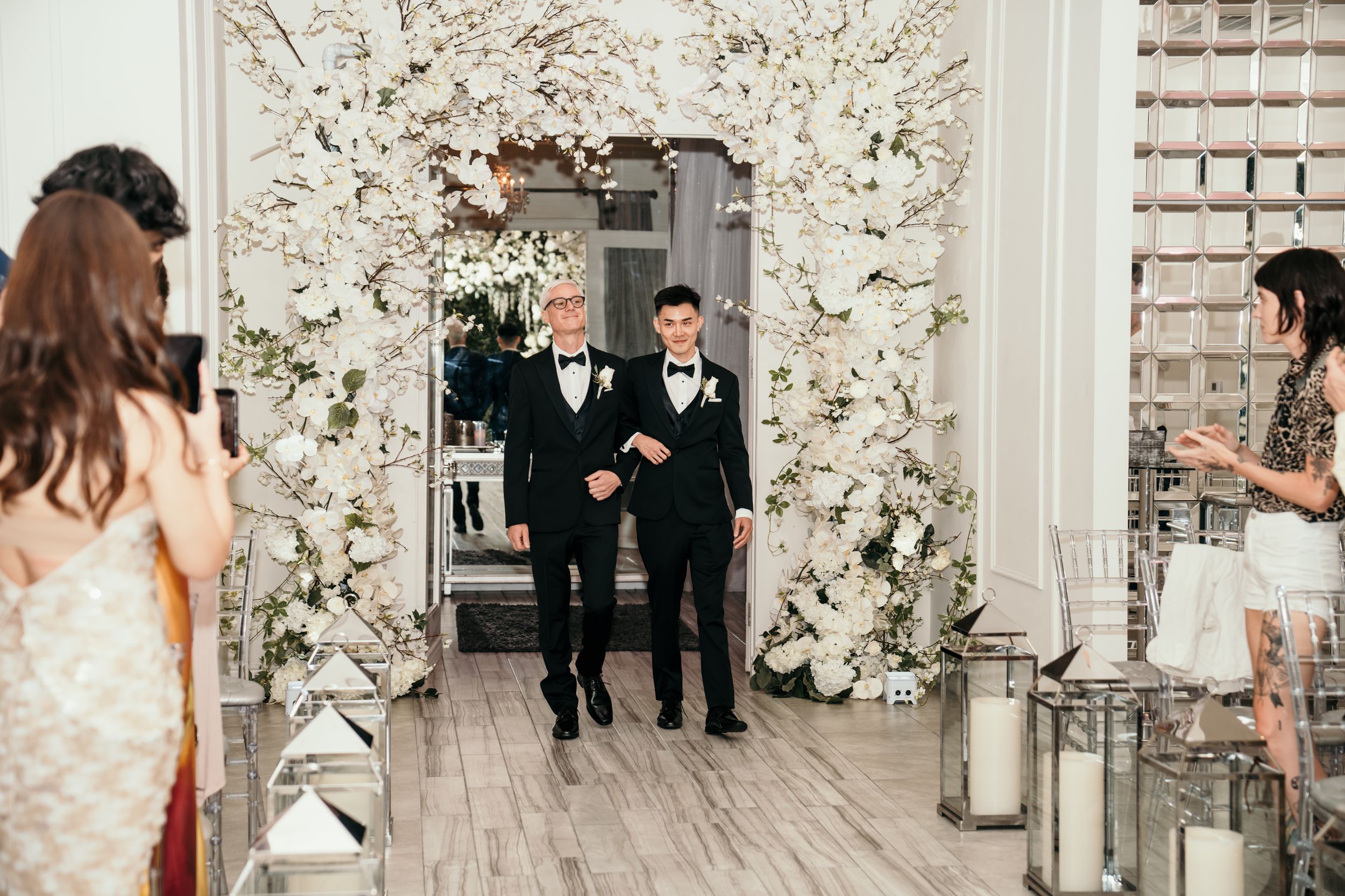 Wedding ceremony entrance decorated with white floral arch and elegant decor.