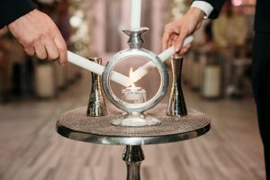 Hands pour champagne into a glass pyramid setup on a decorative silver tray during a celebration event.
