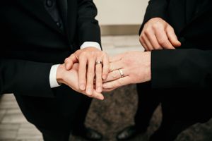 Close-up view of hands showing an engagement or wedding ring during an intimate moment.
