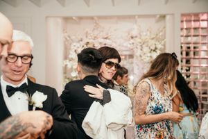 A blurred intimate moment at a formal wedding reception with guests gathered in an elegantly decorated venue.