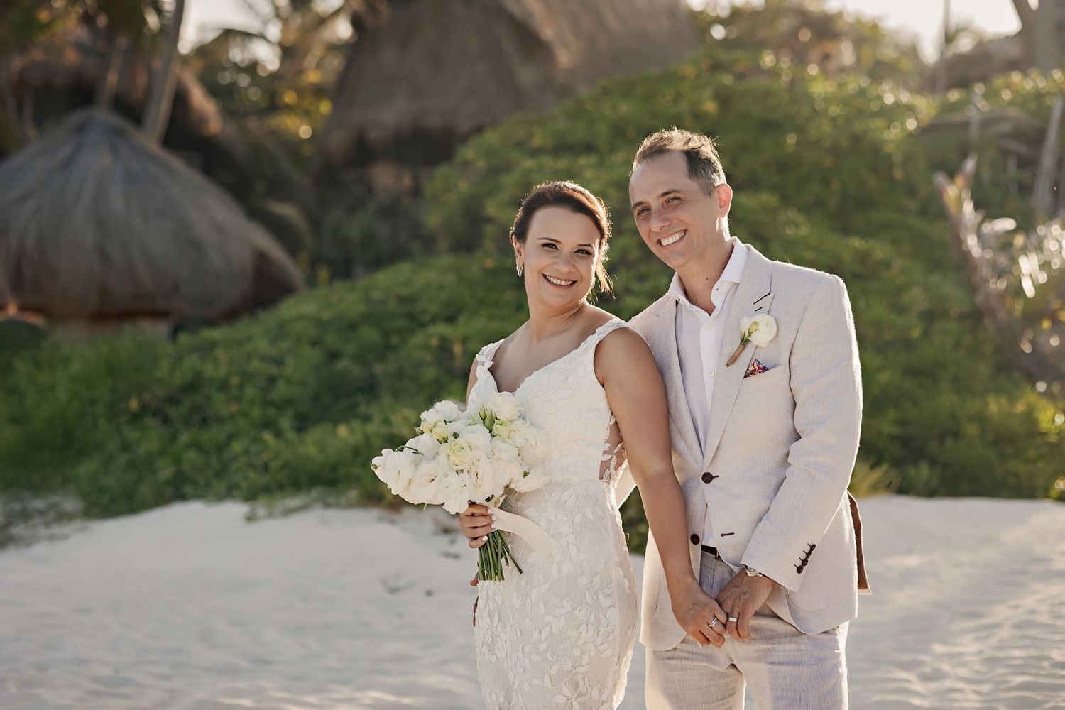 Bride and groom smile holding hands during their beach wedding at Alquimia Boutique Hotel in Tulum, Mexico.