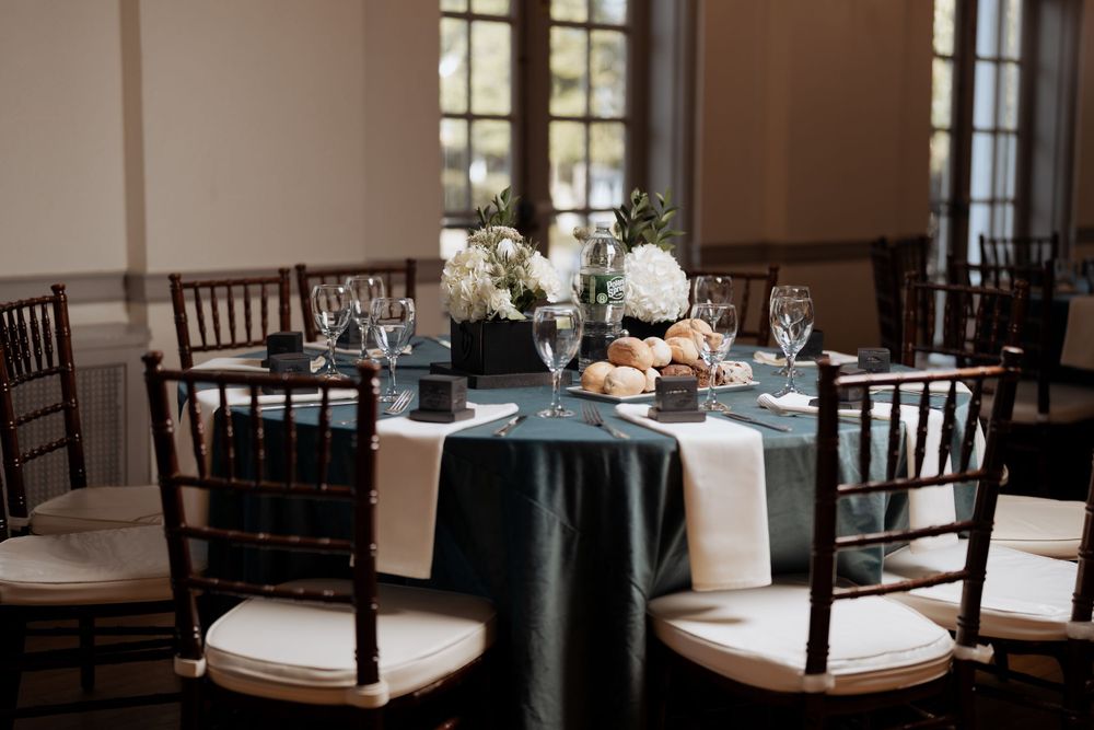 Elegant table setting with white floral centerpieces and black chiavari chairs.