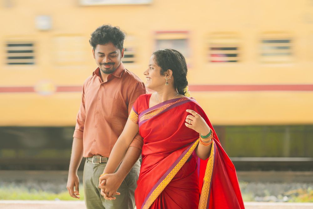Couple in traditional Indian dress walk together against a yellow wall background.