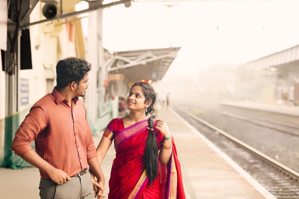 Two people in traditional Indian attire having a conversation while waiting on a misty train platform.