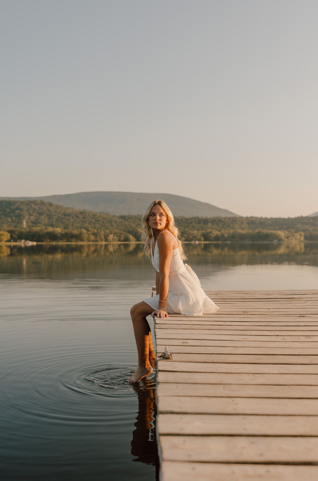 Bride in white dress holds wildflower bouquet during golden hour in field.