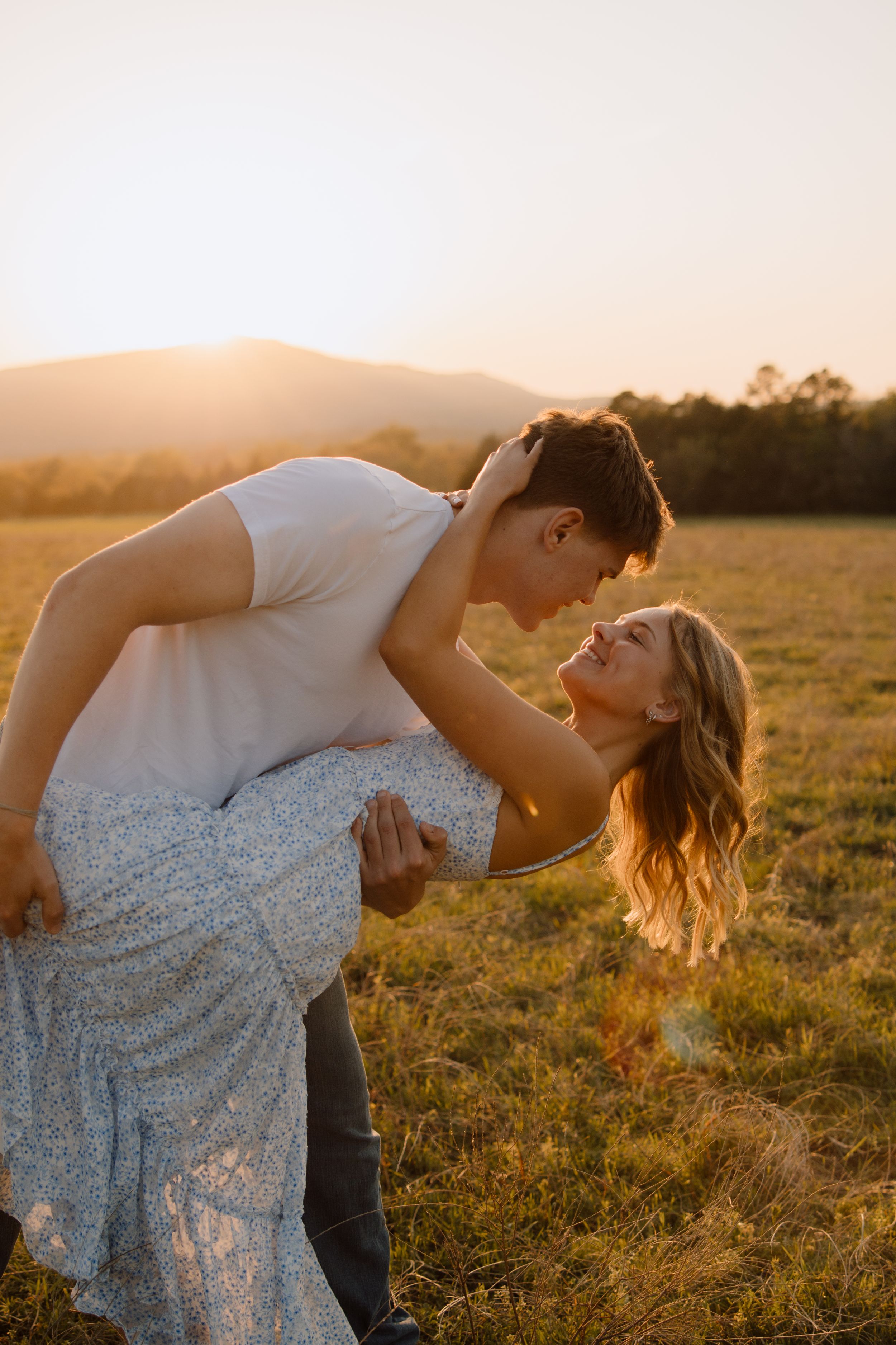 A romantic couple shares an intimate dip pose in a sunset field.