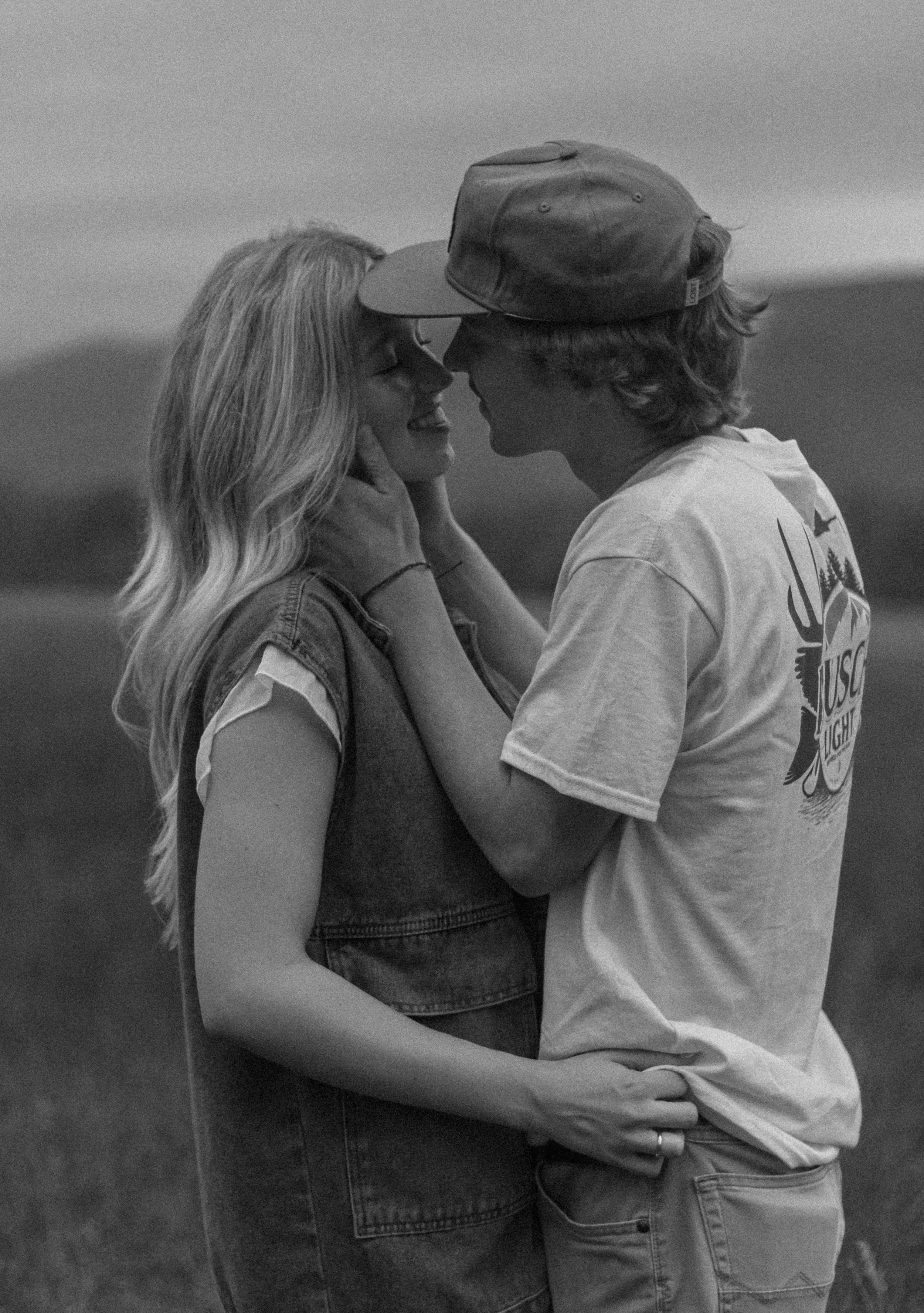 Black and white photo series capturing romantic intimacy and connection between a couple in an outdoor field setting.