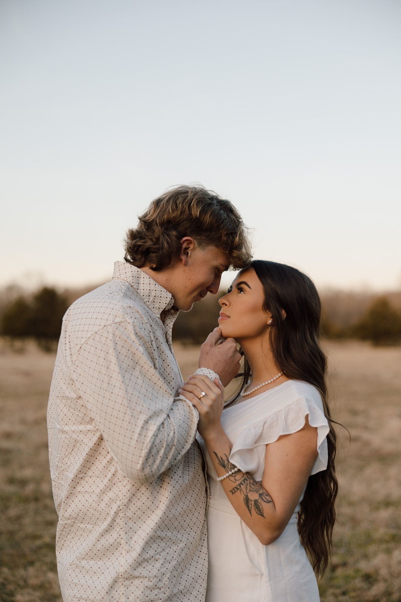 A romantic couple embraces tenderly in a desert landscape during golden hour.