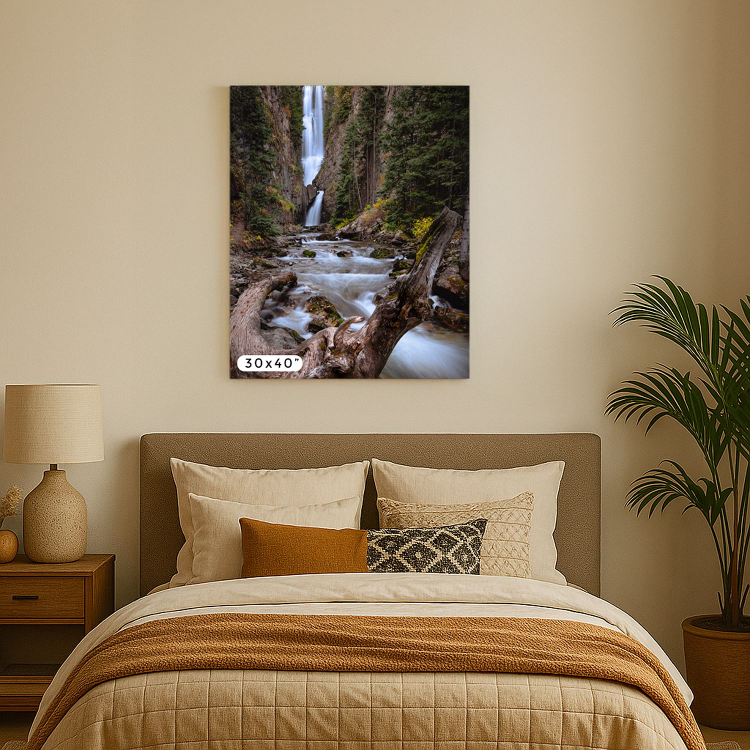 Bedroom interior with waterfall canvas art, brown bedding, decorative pillows, bedside table and potted palm plant.