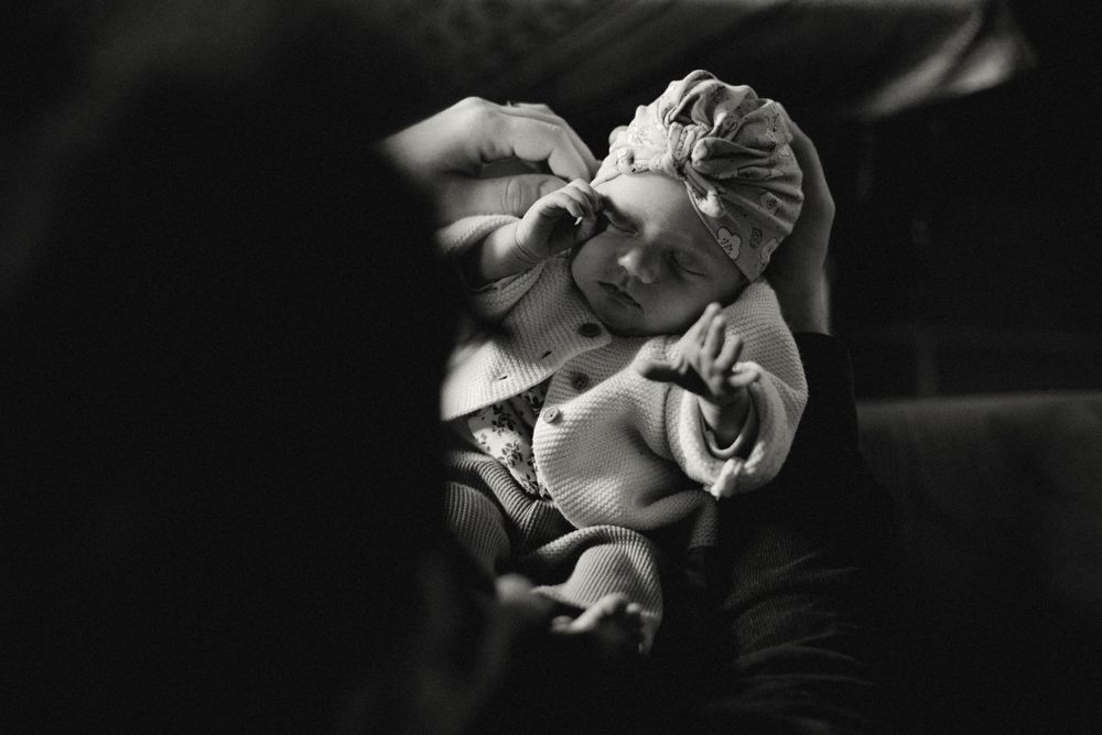 Black and white close-up of a sleeping newborn wearing a delicate bonnet.