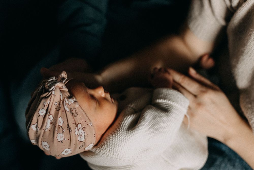 Close-up shot of a peaceful sleeping newborn wearing a beige bonnet.