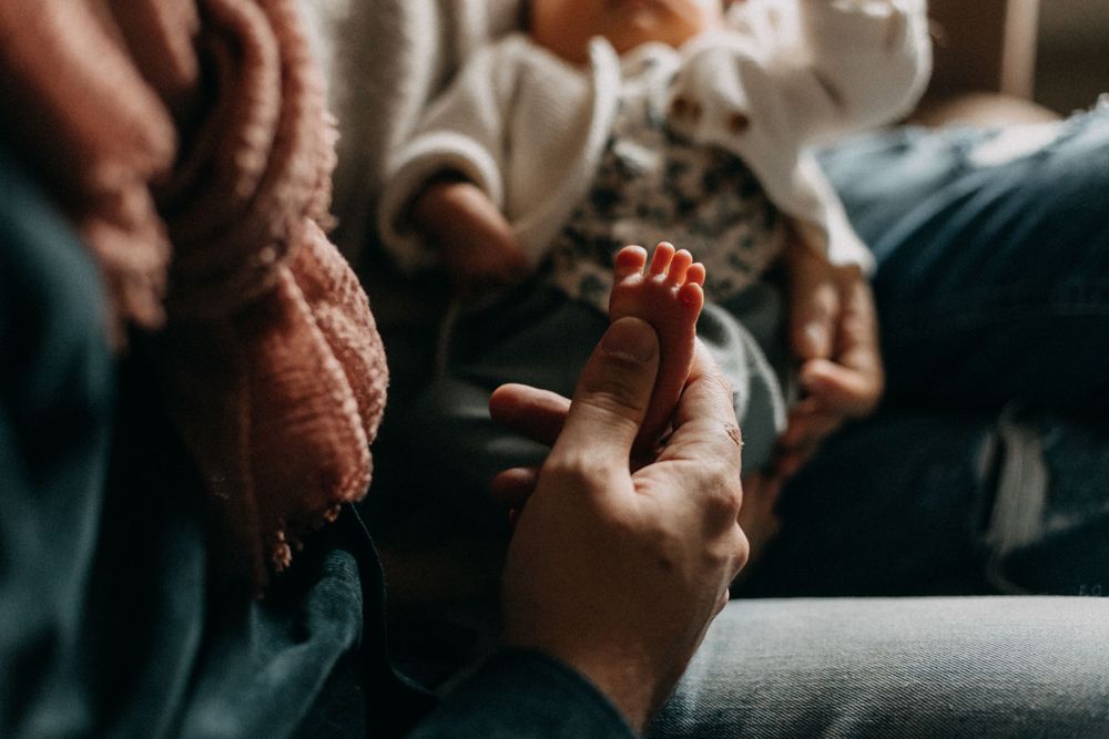 Close-up of tiny baby feet being gently held by caring hands.
