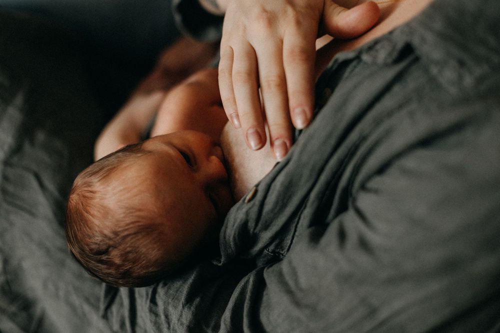 Close-up view of gentle hands cradling a sleeping newborn baby against soft fabric.