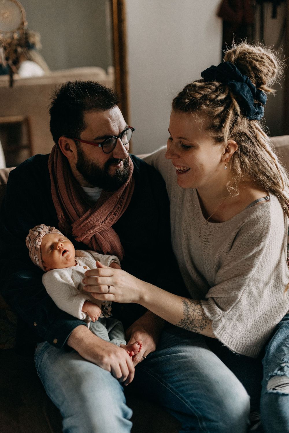 A tender moment shared between parents and their newborn baby on a cozy sofa.