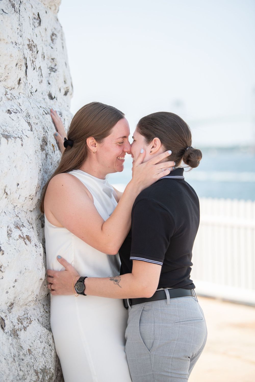Romantic seaside moment between two people in white and black attire.