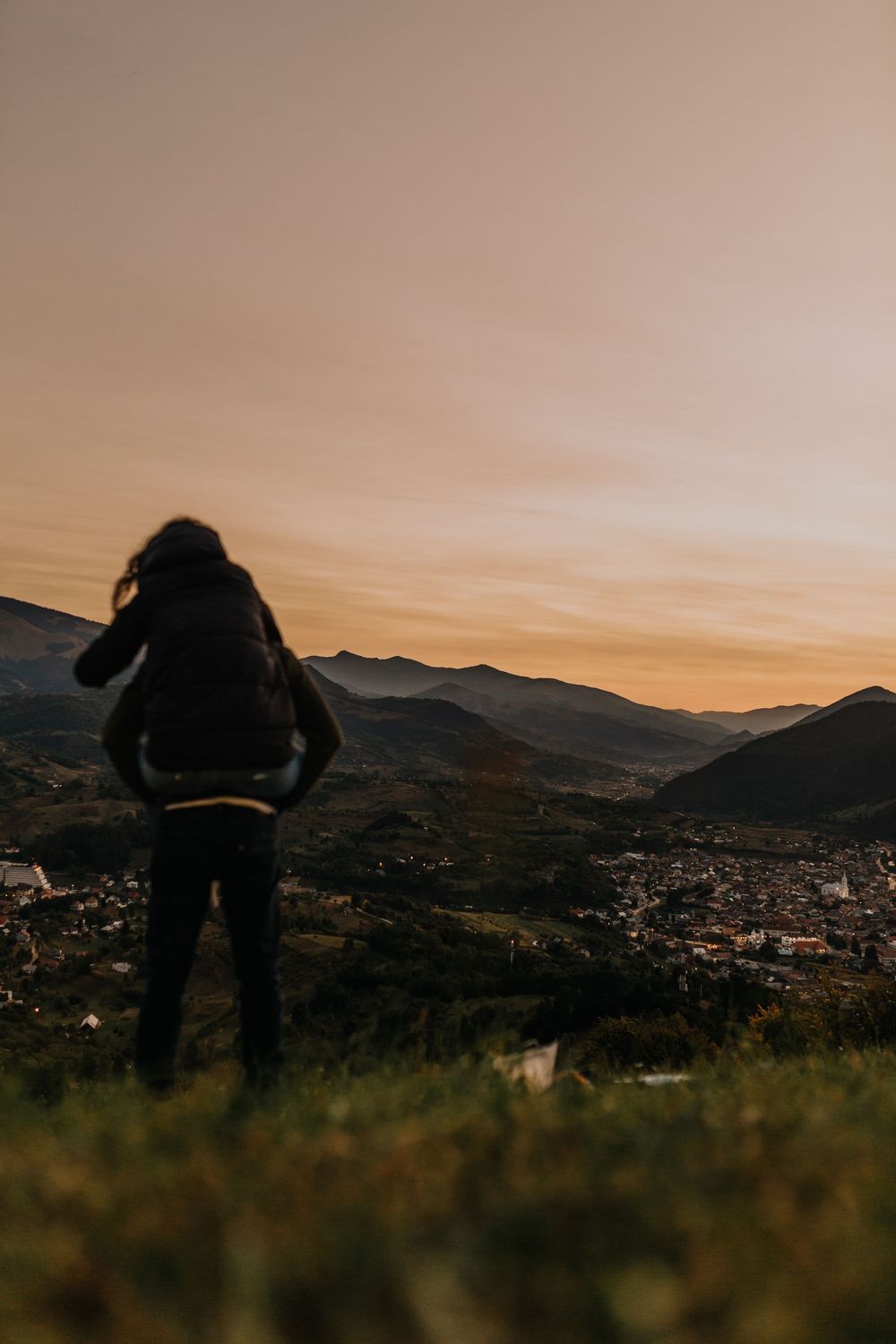 Silhouette of couple embracing on hilltop with panoramic mountain valley sunset view.
