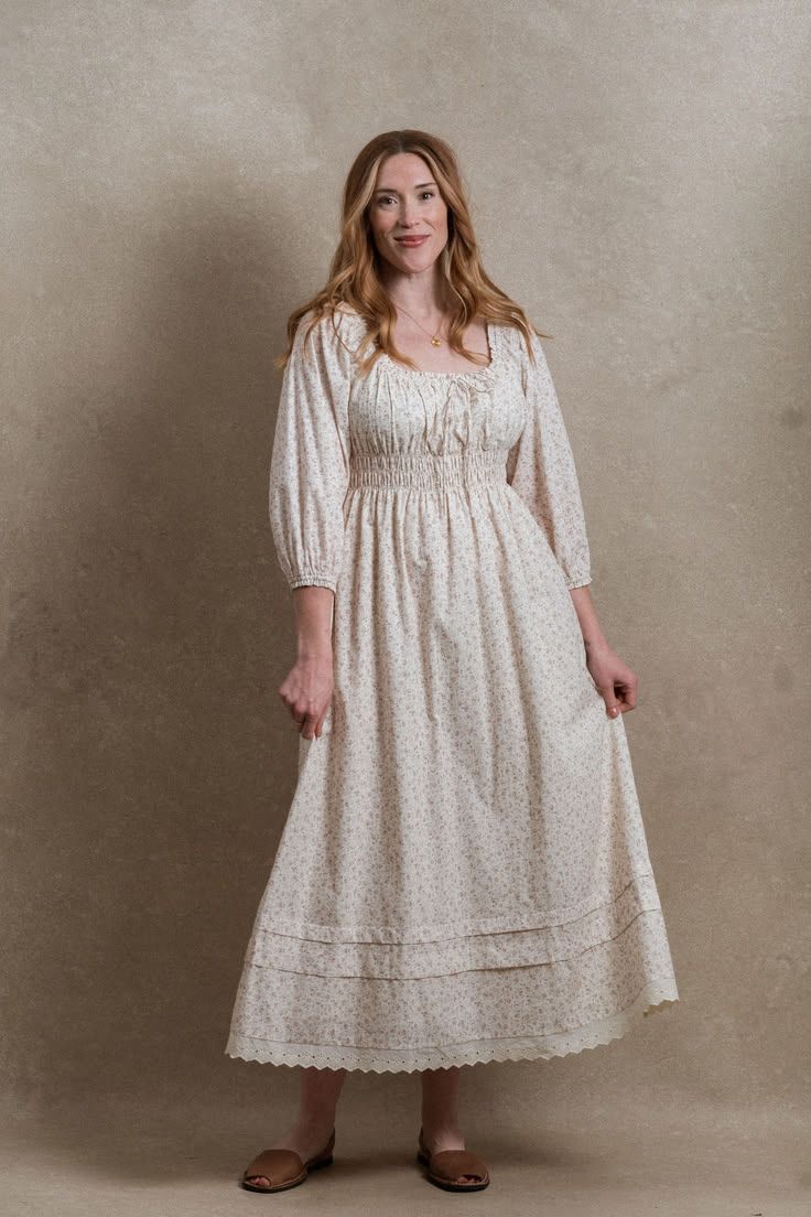 Woman wearing a white floral smocked waist midi dress with puff sleeves and eyelet hem detail.
