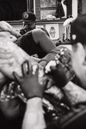 Black and white photo of tattoo artists at work in a studio.