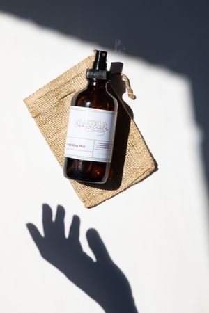 Amber glass bottle with product label casting dramatic shadow on burlap cloth.