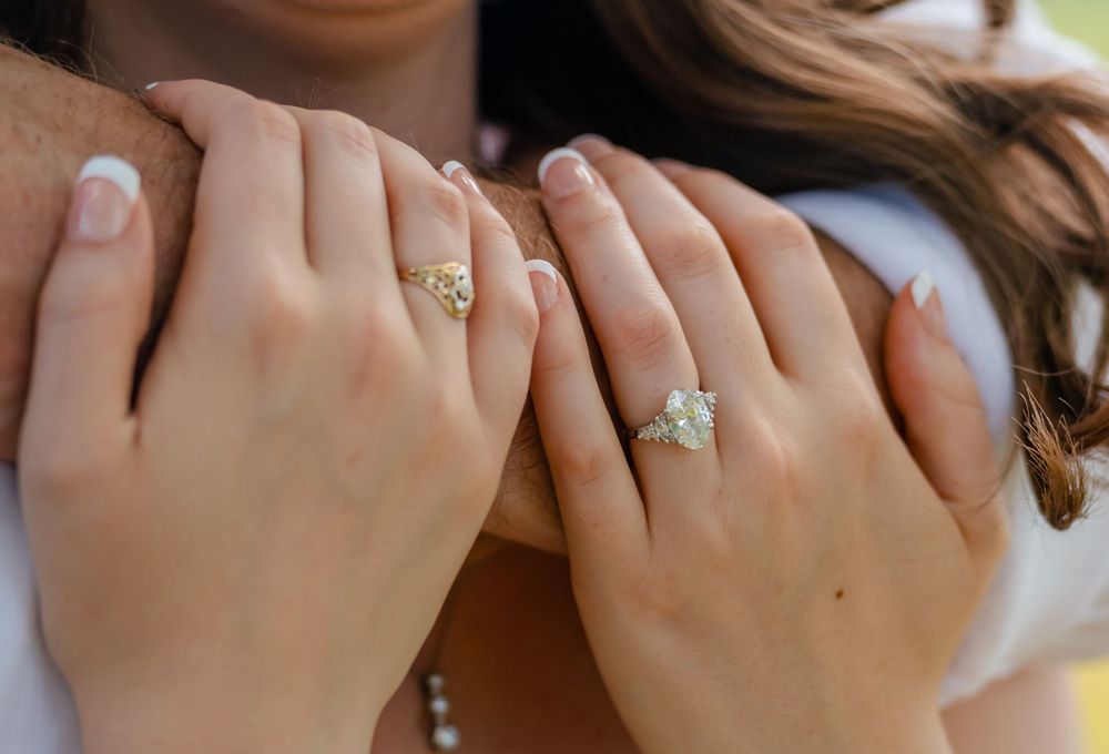 Close-up of couple's hands showing elegant diamond engagement rings, symbolizing love and commitment.