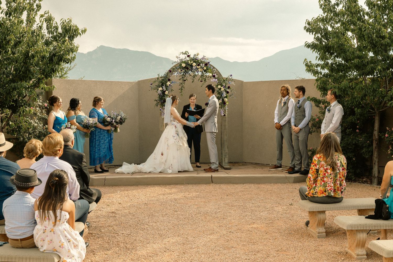 Outdoor wedding ceremony at Hudson Gardens Venue in CO Springs. Couple at alter, mountain backdrop.