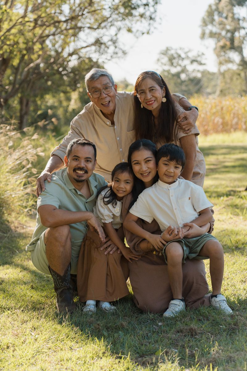 Multigenerational family portrait with grandparents, parents, and two children smiling together in a green park family photoshoot Rouse hill
