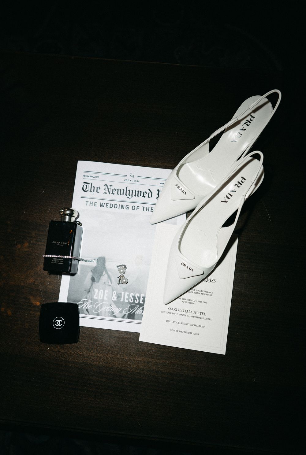 Prada white heels beside Chanel perfume and wedding program newspaper for Zoe and Jesse's ceremony.