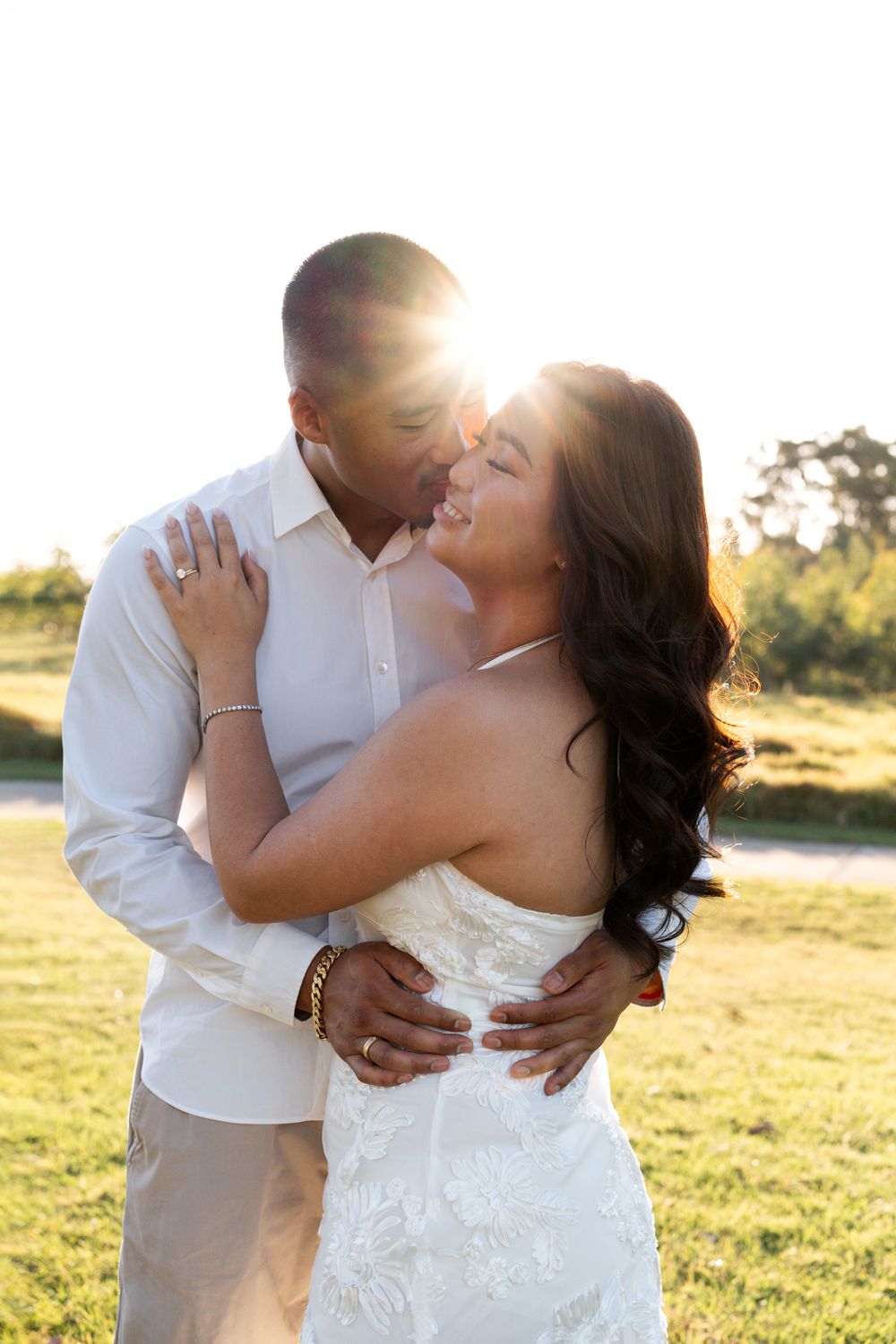 Couple outdoors at golden hour, bride in white lace gown and groom in white shirt, backlit by warm sunset light elopement photoshoot sydney