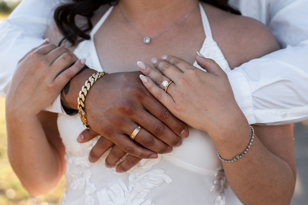 Couple's hands together showing wedding rings, gold chain bracelet, and diamond necklace on bride in white dress photoshoot wedding sydney