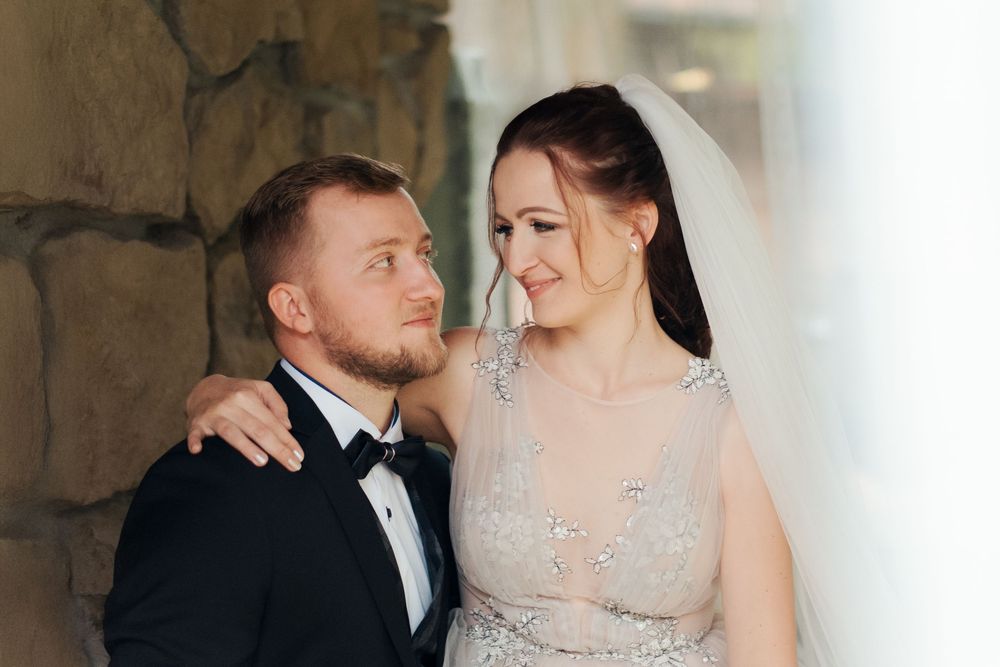 A bride in a beaded gown and veil embraces her groom in a tuxedo, sharing a tender moment at their wedding hunter valley