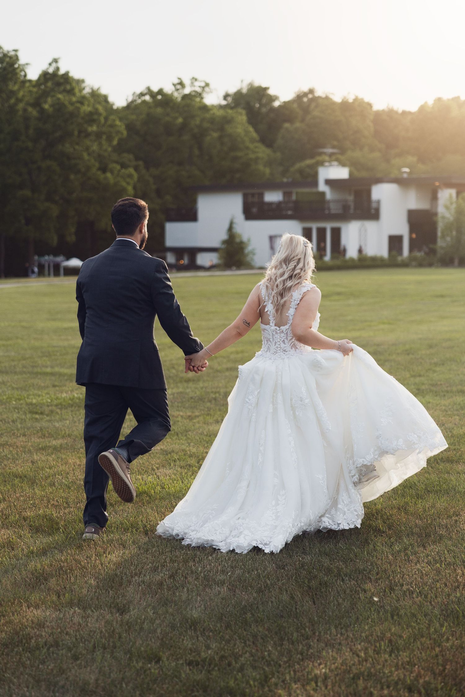 Couple holds hands and runs together at their wedding venue - Southeast Michigan Fine Art Wedding Photographer