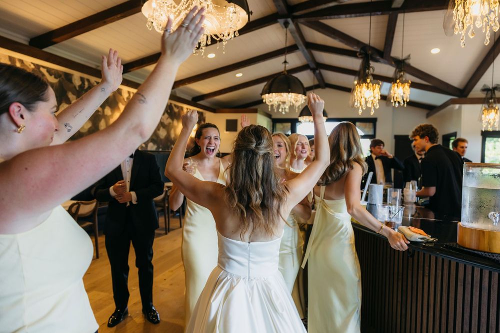 Bride in white gown celebrating with bridesmaids in yellow dresses captured by candid photographer in Wisconsin