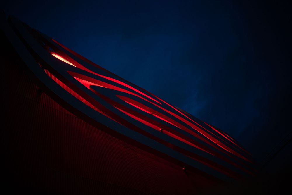 Close-up of red illuminated vents on a dark blue car body at night.